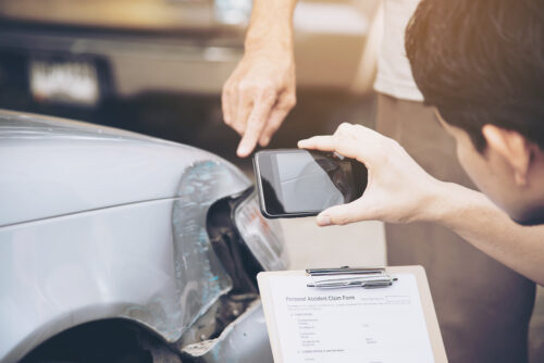 insurance adjuster person taking picture of damages on a car