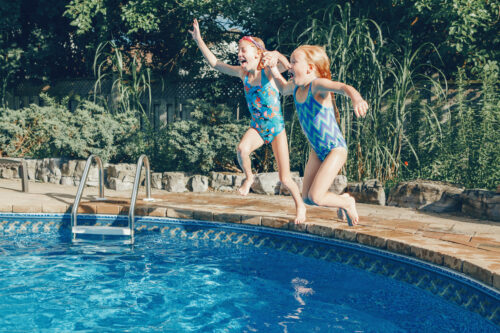 two young girls jumping into a swimming pool