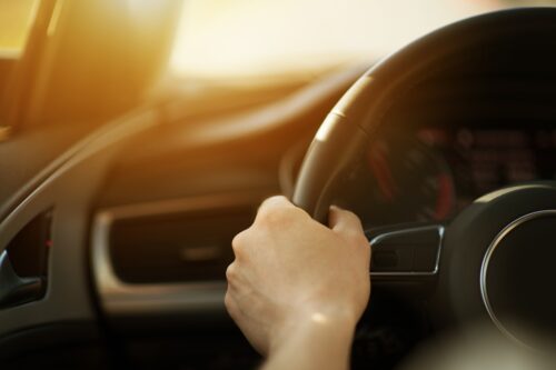 Modern Sporty Car Handling Concept Photo. Men Driving His Car. Hand on Steering Wheel Closeup.