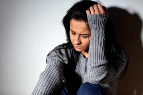 people, grief and domestic violence concept - unhappy woman sitting on floor and crying
